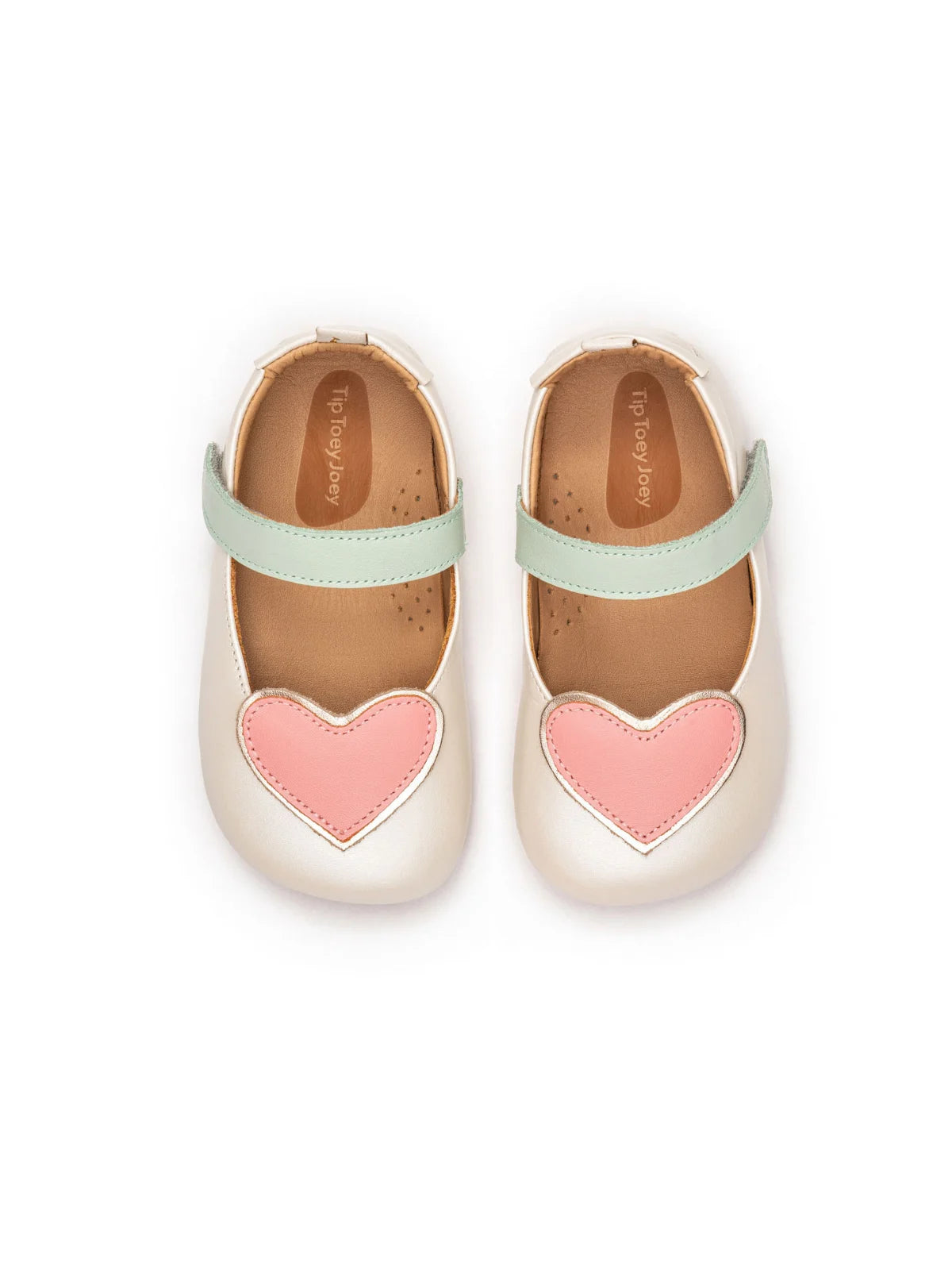 Overhead view of antique white baby shoes featuring pink heart patches and a wide toe box for natural foot growth.