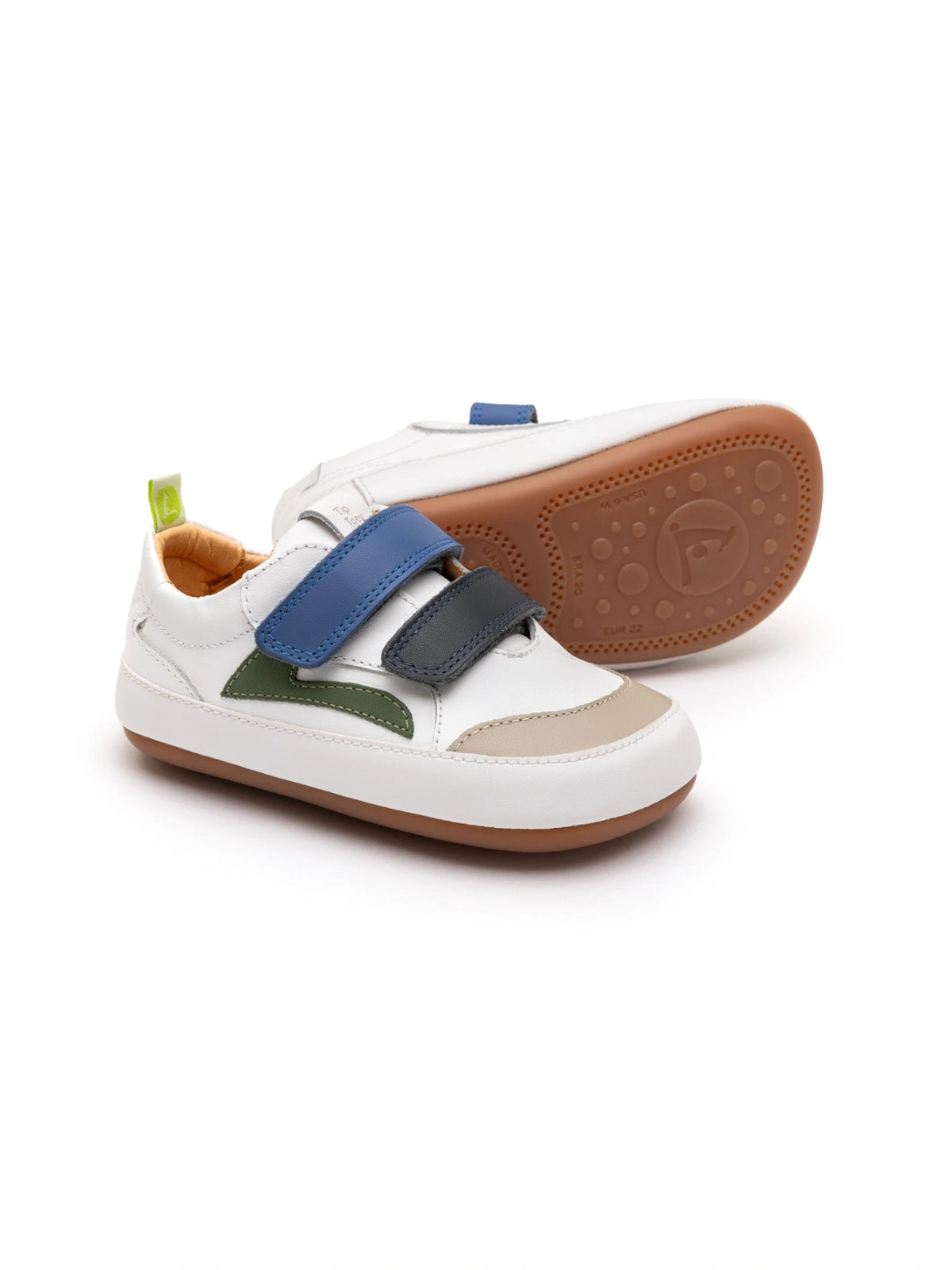 White leather baby sneakers with navy and blue tang accents, featuring double straps and a gum rubber sole.