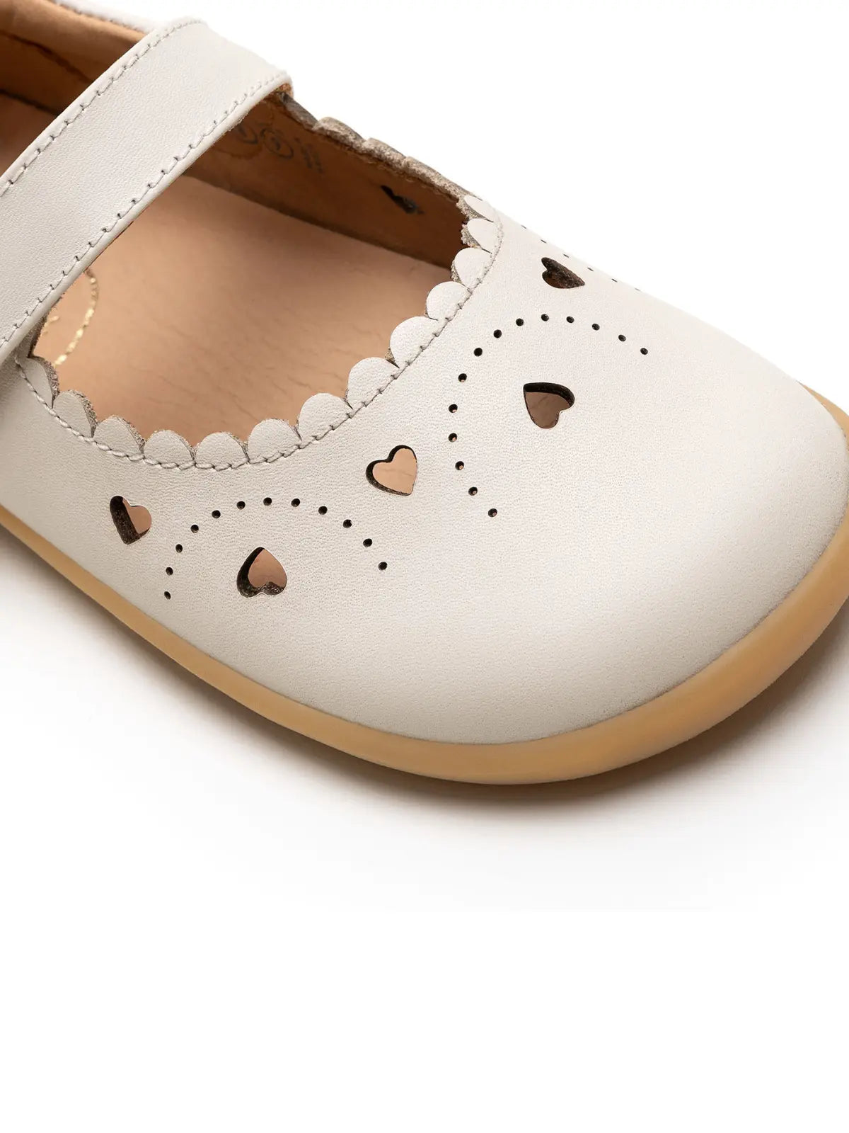 Close-up of the delicate scalloped edges and intricate heart laser cut-outs on the tapioca kids shoe.