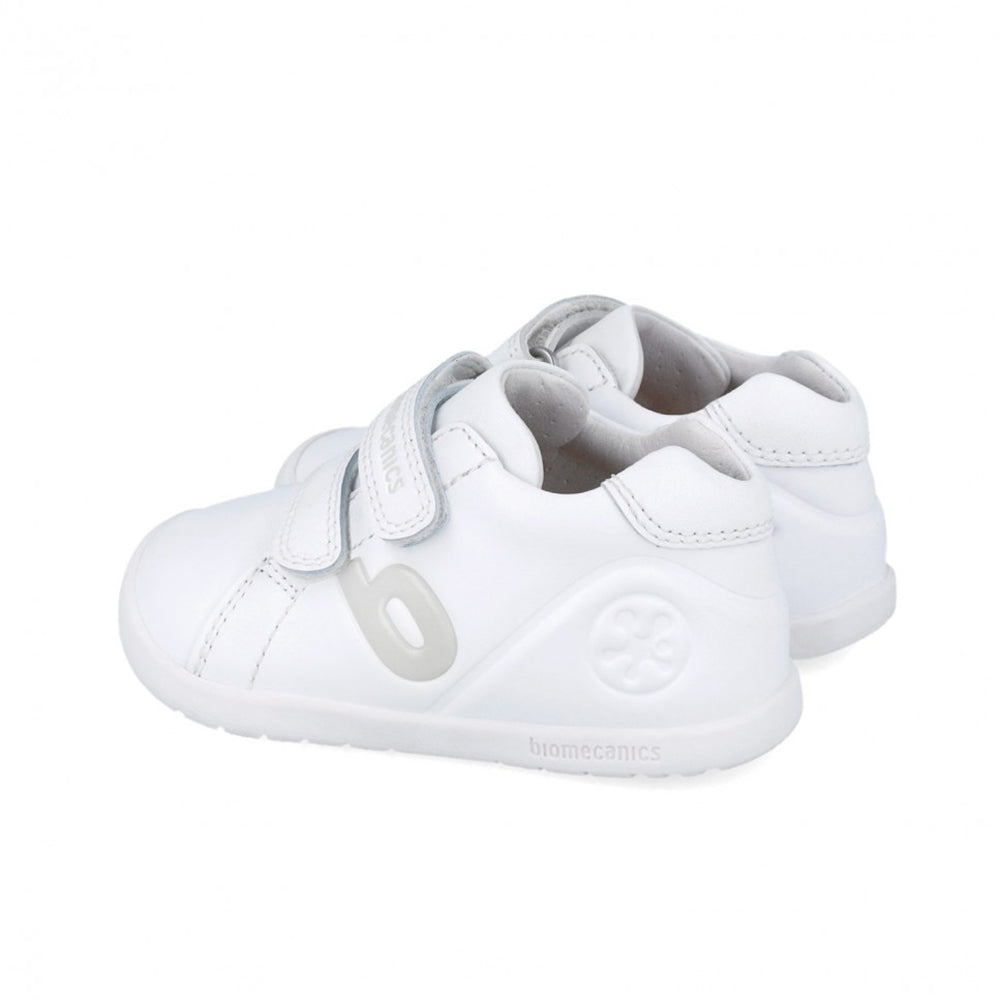 White children's shoes with velcro straps on a white background