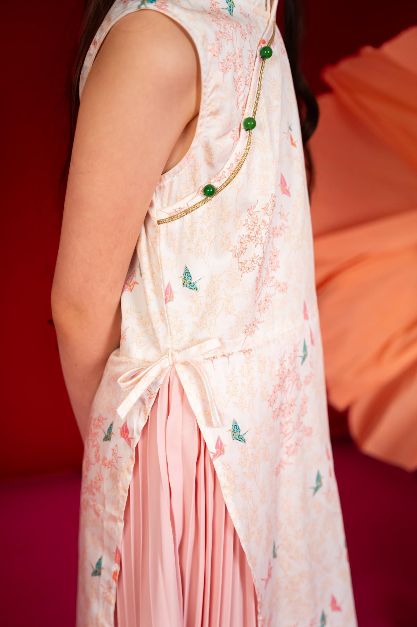 Girl wearing a sleeveless patterned dress with pink skirt.