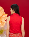 Woman in red top and patterned skirt, back view.